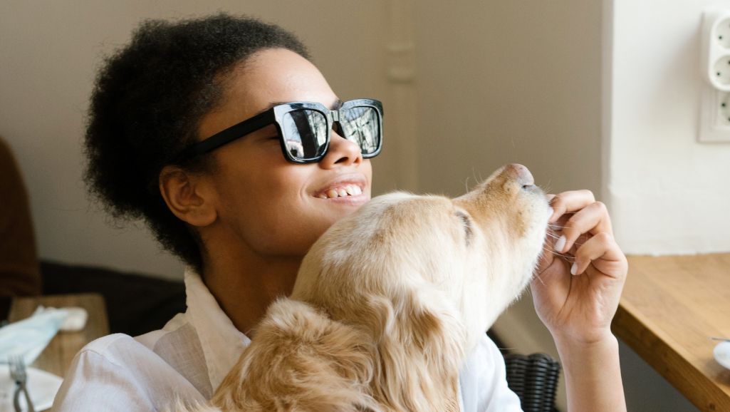 A blind woman plays with her dog. Website accessibility makes online tools & content accessible to more people.